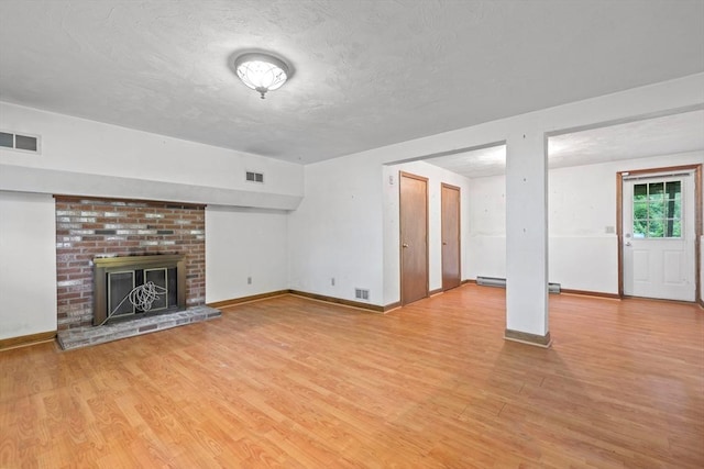 18 Bismark St, Dedham, MA 02026 - unfurnished living room with wood finished floors, a brick fireplace, and a textured ceiling