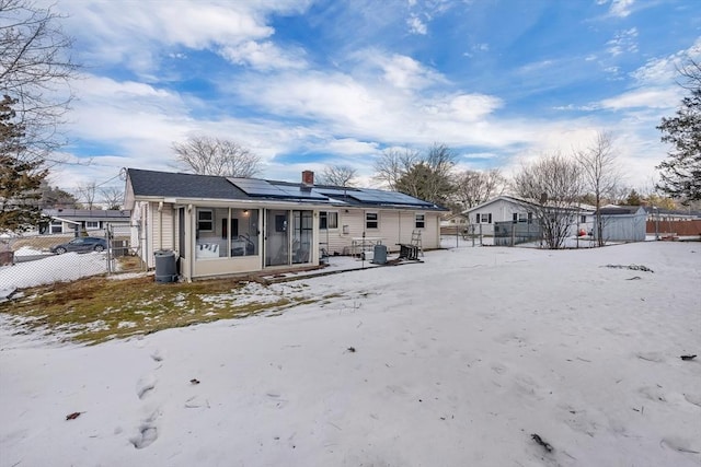 snow covered property with a sunroom and solar panels