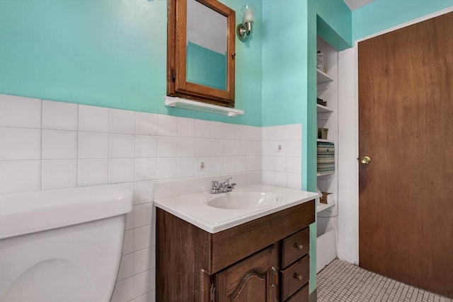 bathroom featuring vanity, tile walls, and toilet