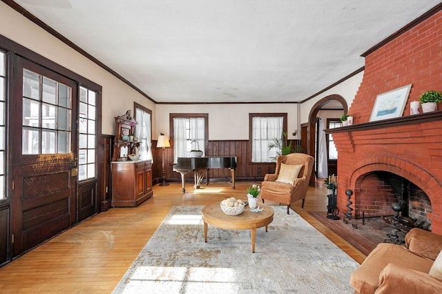 living area with a brick fireplace, light hardwood / wood-style flooring, and crown molding