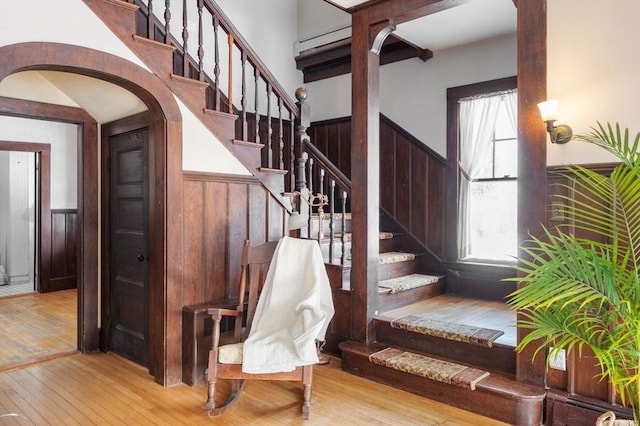 staircase with a healthy amount of sunlight, hardwood / wood-style floors, and wooden walls