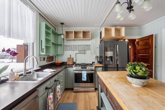 kitchen with crown molding, wooden walls, sink, light hardwood / wood-style flooring, and stainless steel appliances