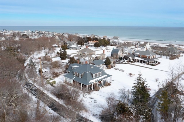 snowy aerial view featuring a water view and a view of the beach