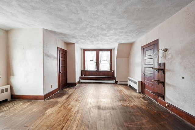 interior space featuring dark hardwood / wood-style floors, radiator, and a baseboard heating unit