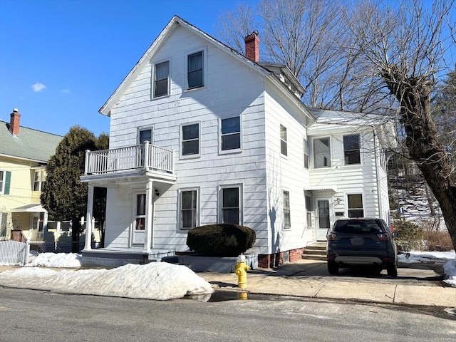 view of front of home with a chimney and a balcony