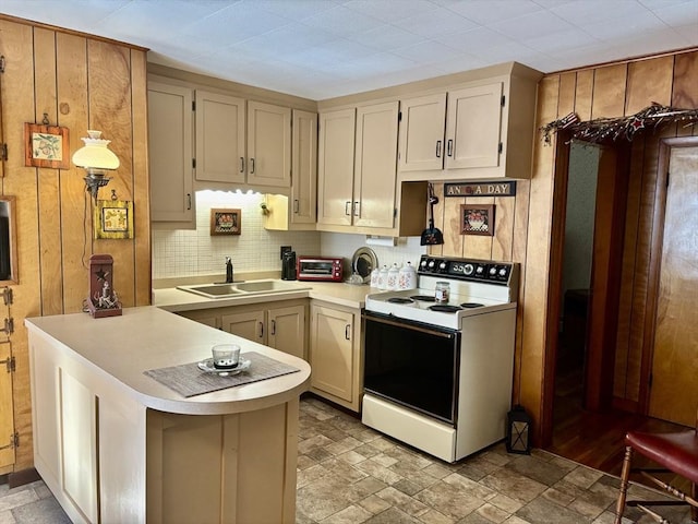 kitchen featuring light countertops, a peninsula, stone finish floor, white electric range, and a sink