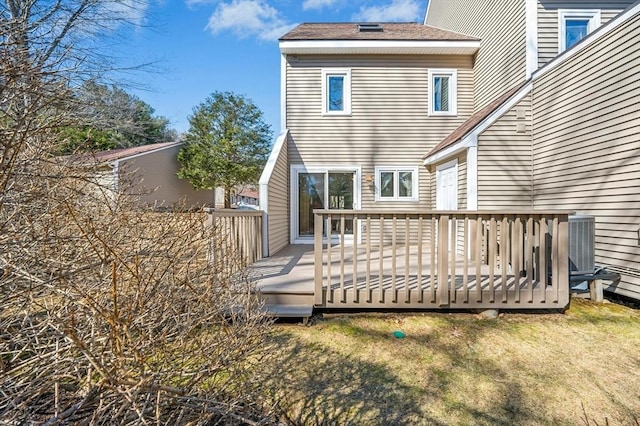 back of house featuring a lawn, a wooden deck, and central AC