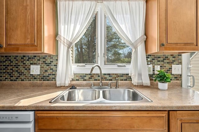 kitchen with dishwashing machine, brown cabinets, decorative backsplash, and a sink