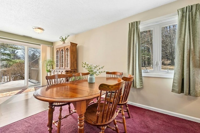 carpeted dining room with a textured ceiling and baseboards