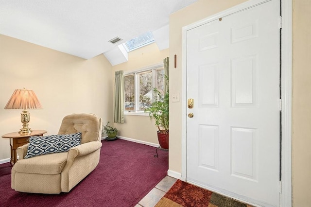 carpeted foyer with vaulted ceiling with skylight, baseboards, and visible vents