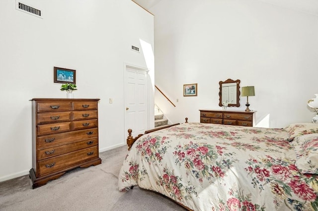 bedroom featuring visible vents, light carpet, baseboards, and a towering ceiling