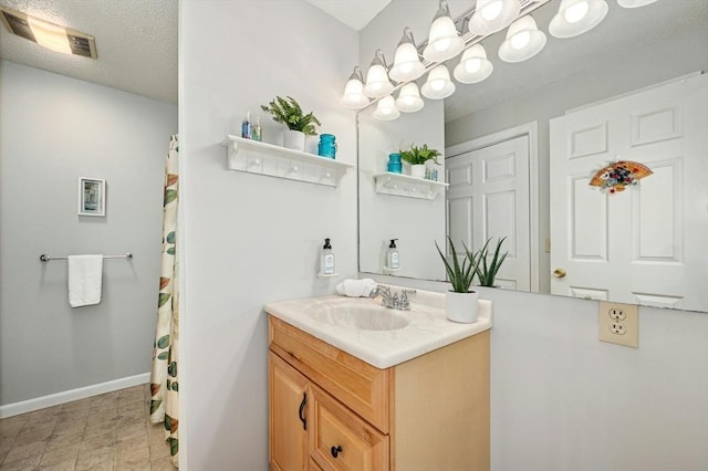 bathroom featuring visible vents, baseboards, a textured ceiling, and vanity