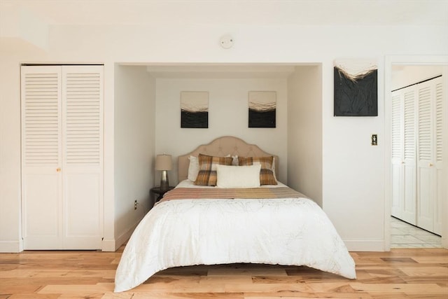 bedroom with multiple closets and light hardwood / wood-style flooring