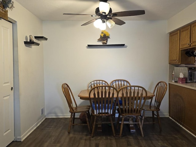 dining room with dark wood-style floors, a ceiling fan, visible vents, and baseboards