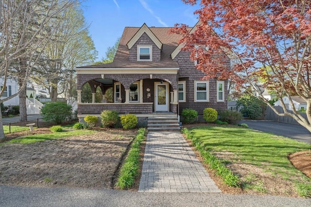 view of front of house featuring fence, covered porch, and a front yard