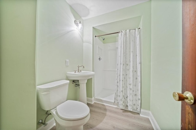 full bath with baseboards, a stall shower, toilet, and wood finished floors