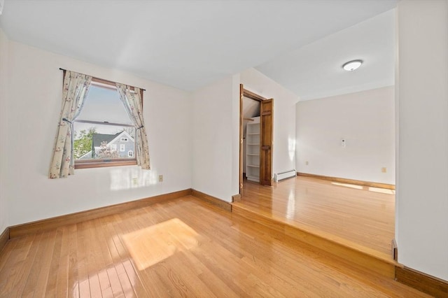 unfurnished room with baseboards, baseboard heating, and hardwood / wood-style flooring