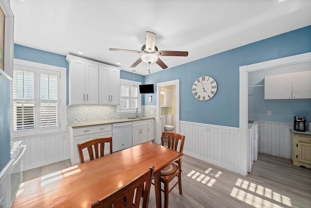dining area with ceiling fan, wainscoting, and light wood-type flooring