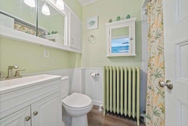 bathroom with vanity, ornamental molding, radiator, wood finished floors, and toilet