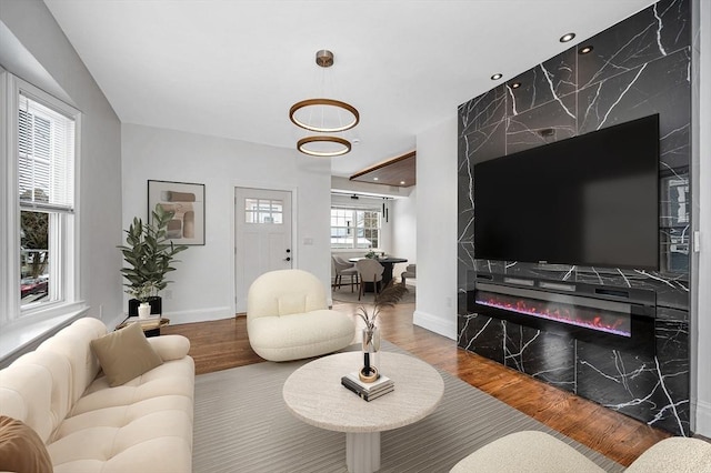 living area with recessed lighting, a fireplace, wood finished floors, and baseboards