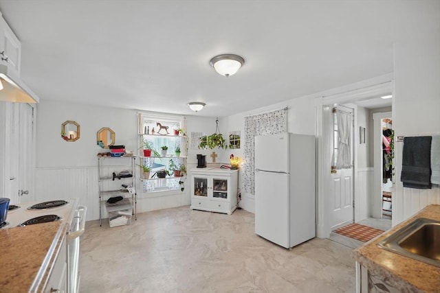 kitchen with white appliances, white cabinetry, and sink