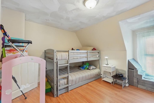 bedroom with vaulted ceiling and hardwood / wood-style flooring