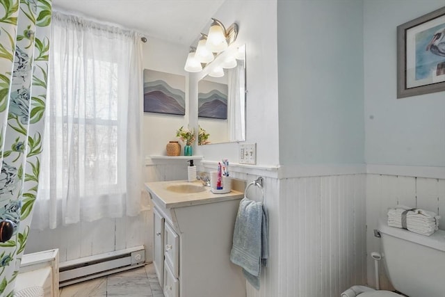 bathroom featuring toilet, vanity, and a baseboard heating unit