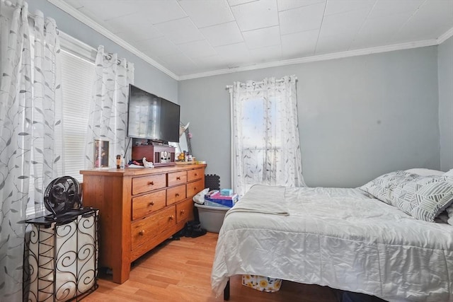 bedroom featuring ornamental molding and light hardwood / wood-style flooring