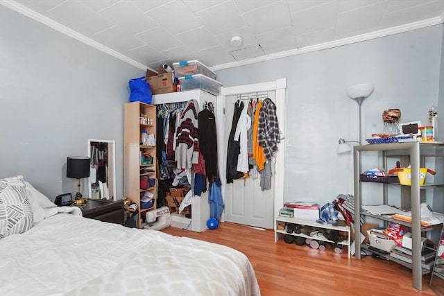 bedroom with a closet, hardwood / wood-style floors, and ornamental molding