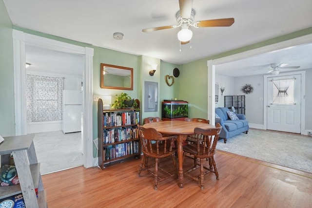 dining area with ceiling fan, electric panel, and light hardwood / wood-style flooring