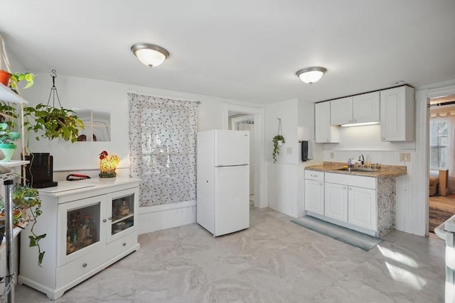 kitchen with sink, white fridge, and white cabinetry