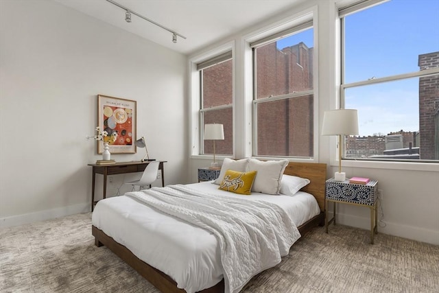 carpeted bedroom featuring rail lighting