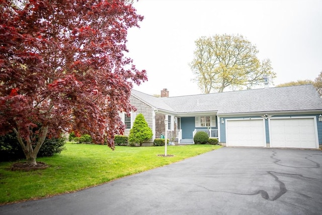 ranch-style home with a garage, driveway, a chimney, a front lawn, and a porch