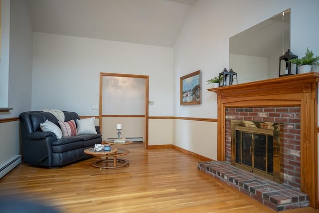 living area with wood finished floors, a brick fireplace, vaulted ceiling, baseboards, and baseboard heating