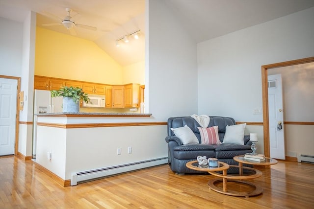 living area featuring baseboard heating, light wood-style floors, a ceiling fan, high vaulted ceiling, and baseboards