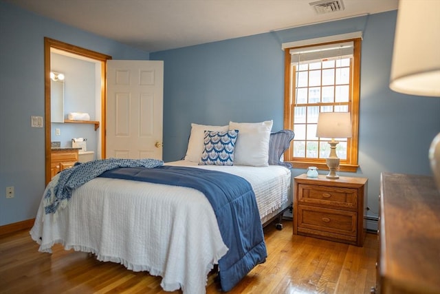 bedroom featuring hardwood / wood-style floors, a baseboard radiator, and baseboards