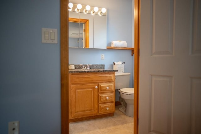 half bath featuring toilet, vanity, and tile patterned floors