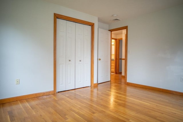 unfurnished bedroom featuring baseboards, light wood-type flooring, and a closet