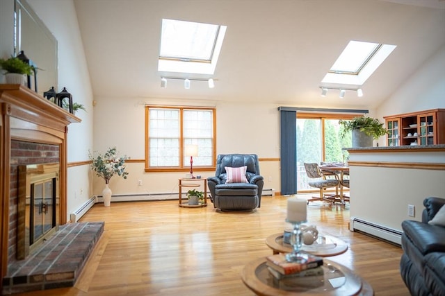 living room featuring a skylight, baseboard heating, a fireplace, vaulted ceiling, and wood finished floors
