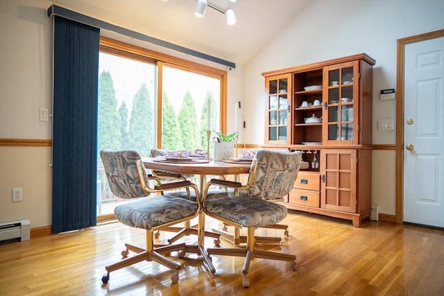 dining room featuring light wood-type flooring, a baseboard heating unit, and high vaulted ceiling
