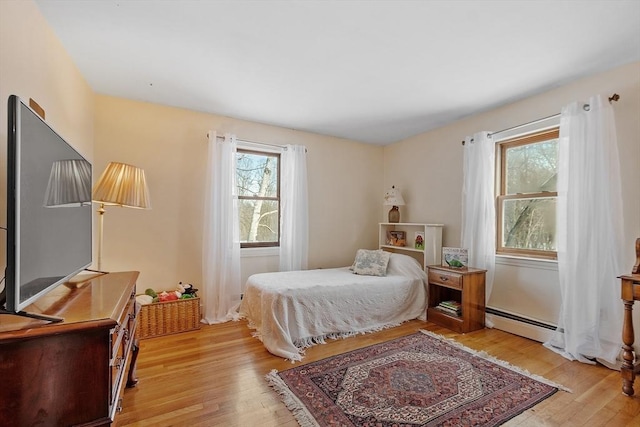 bedroom with light hardwood / wood-style floors and baseboard heating