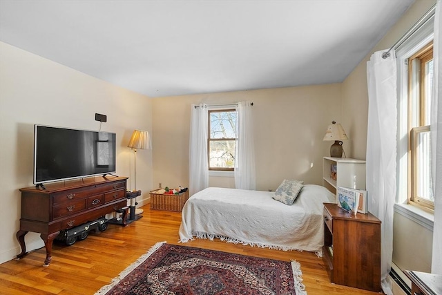 bedroom with a baseboard heating unit and light wood-type flooring