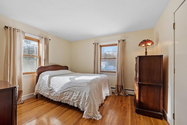 bedroom featuring light hardwood / wood-style floors, multiple windows, and a baseboard radiator