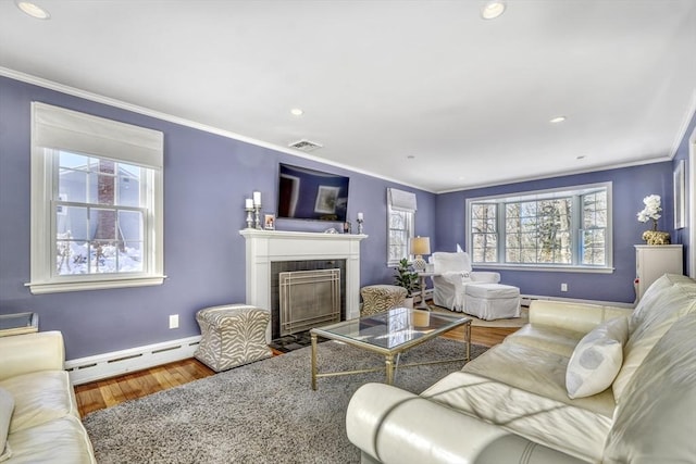 living room with a tiled fireplace, wood-type flooring, ornamental molding, and baseboard heating