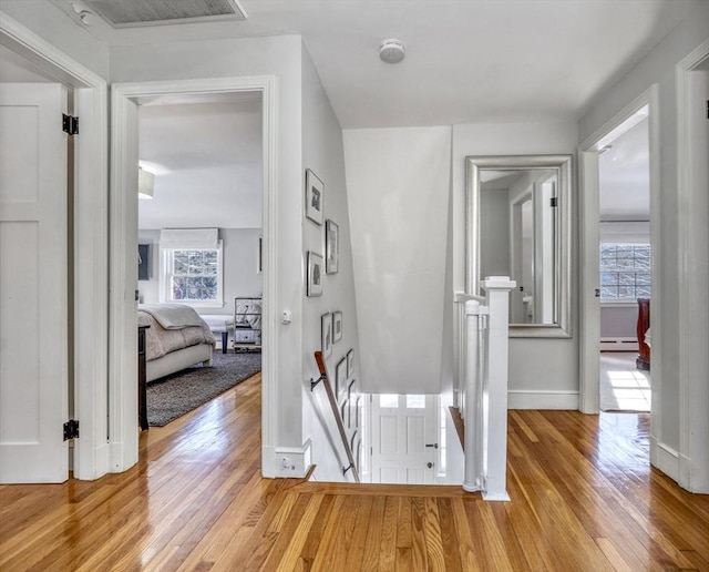 hall featuring a baseboard heating unit and light hardwood / wood-style floors