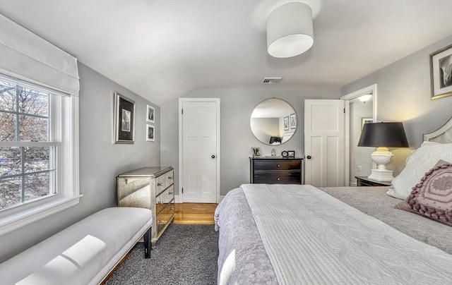 bedroom with multiple windows, vaulted ceiling, and dark hardwood / wood-style floors