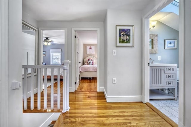 corridor featuring vaulted ceiling and light hardwood / wood-style flooring