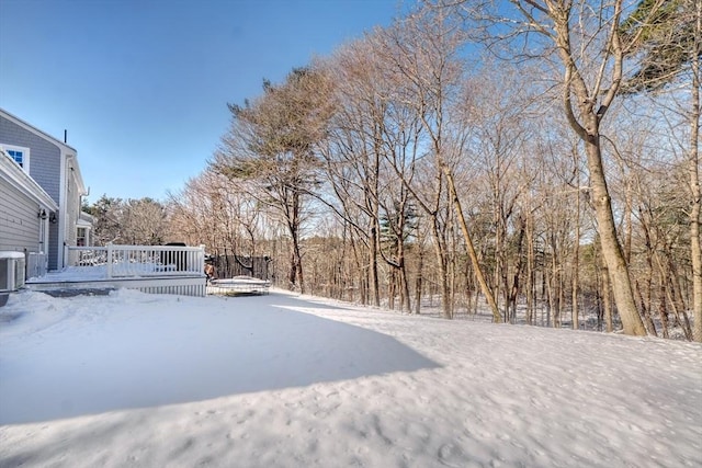 yard layered in snow with cooling unit and a wooden deck