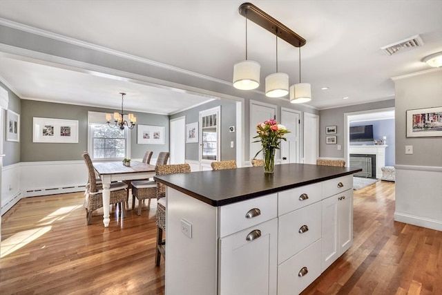 kitchen featuring a kitchen island, decorative light fixtures, white cabinets, ornamental molding, and baseboard heating