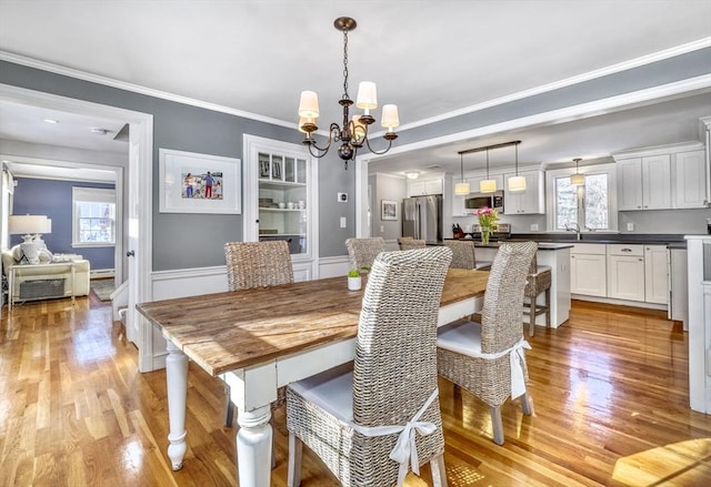 dining area with crown molding, a chandelier, and light hardwood / wood-style flooring